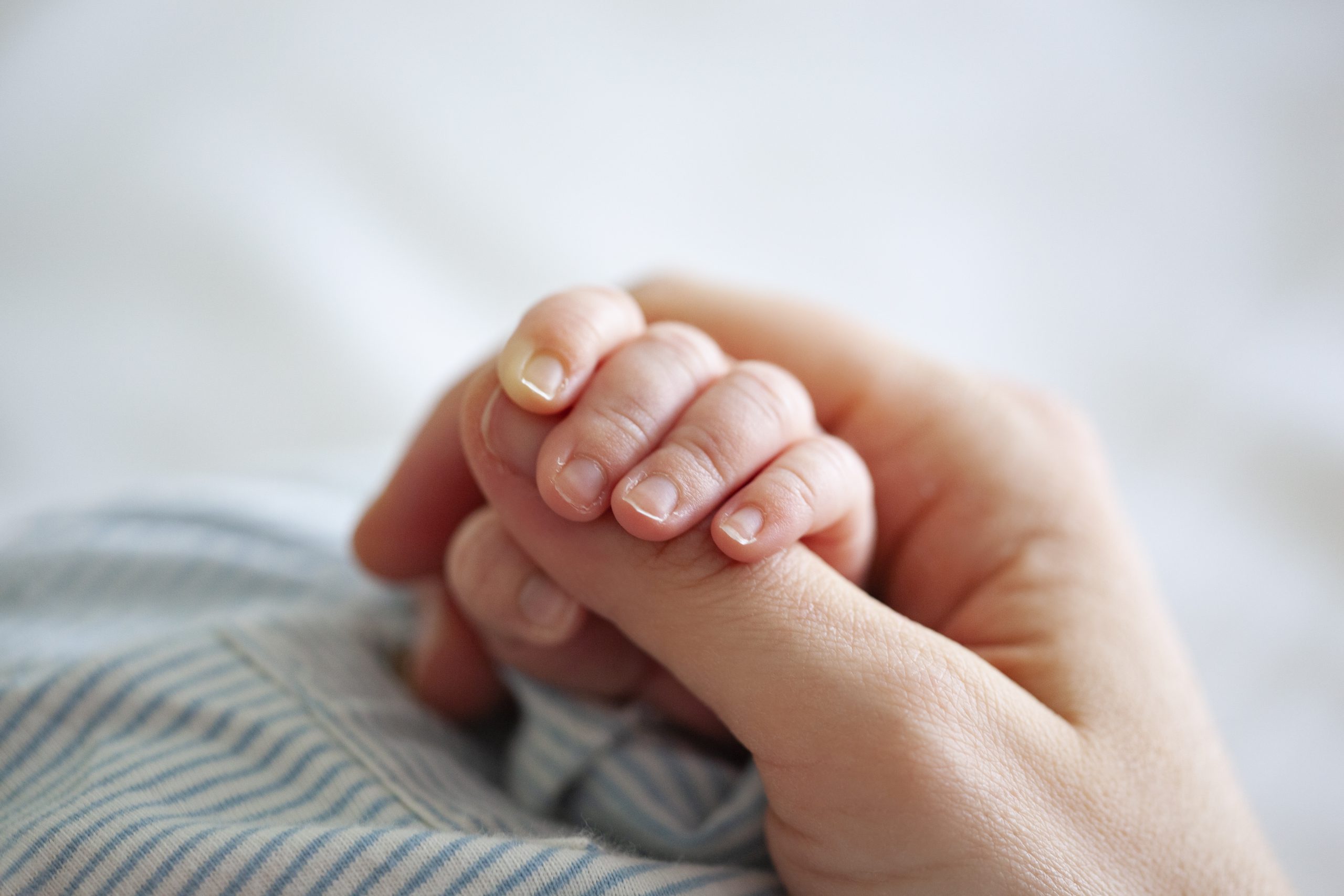 A baby holding someone's finger.