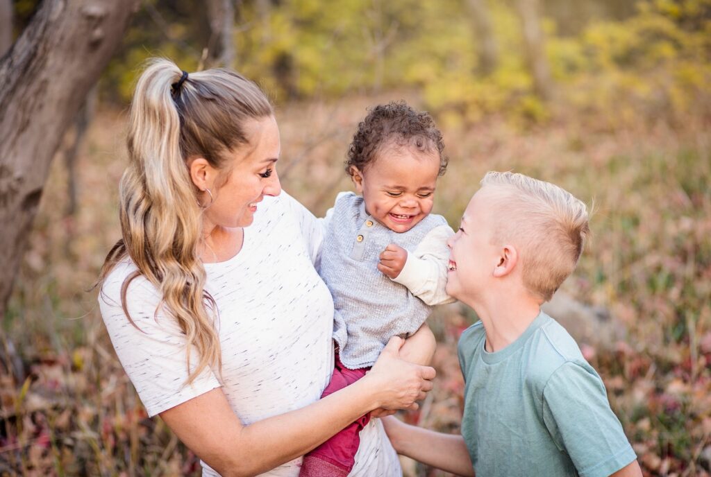 Adoptive mom with biological son holding new adopted baby