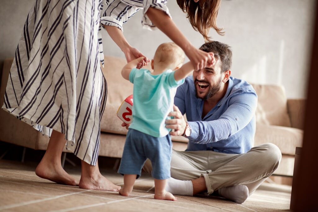 Happy couple helping their adopted baby learn to walk