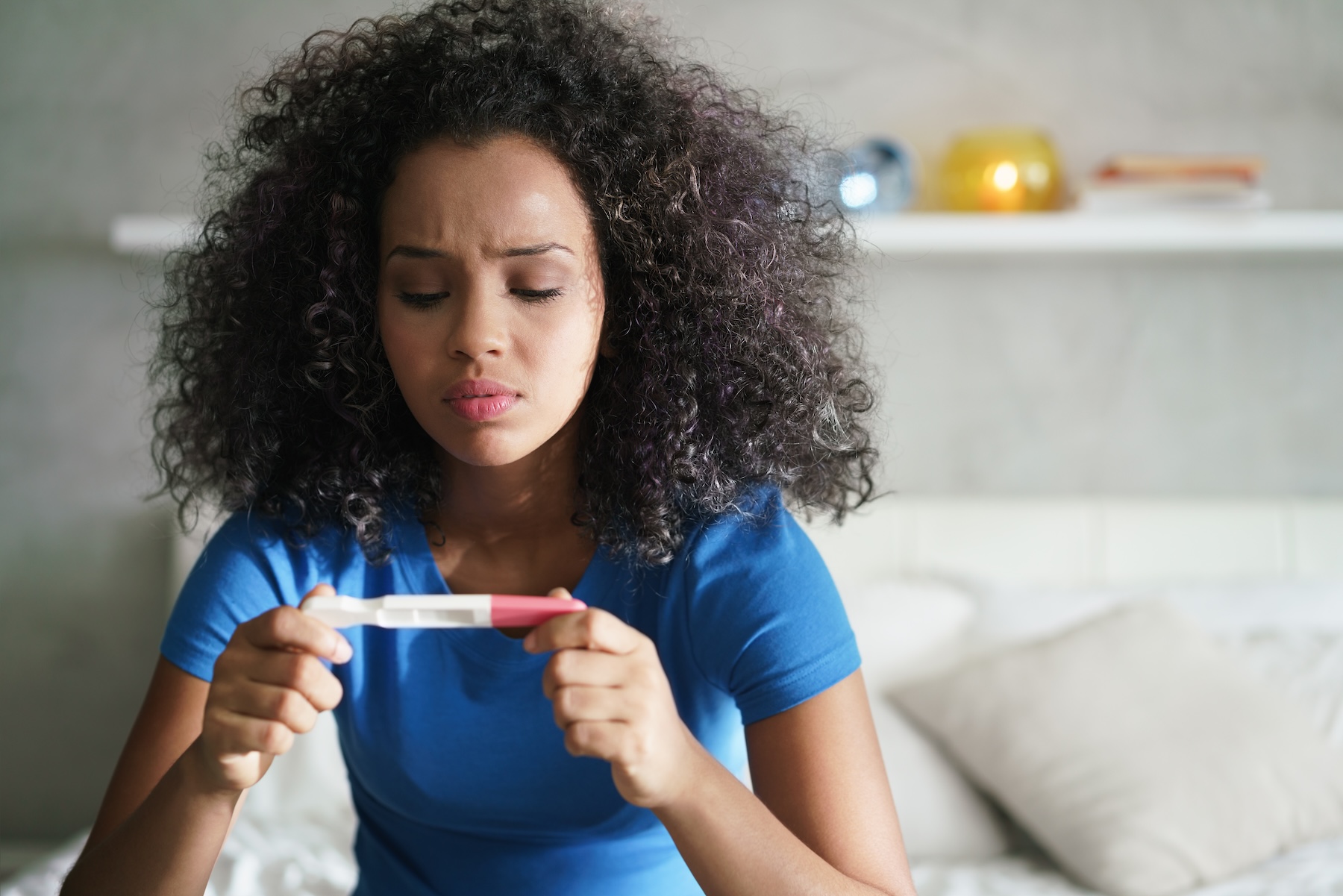 Worried African American woman looking at a positive pregnancy test