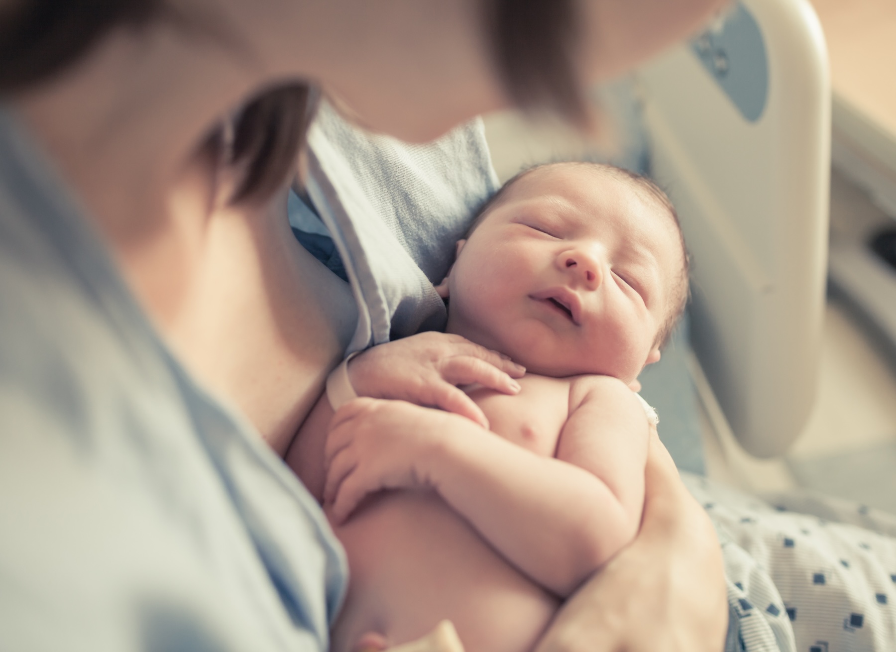Mom holding newborn baby in hospital bed