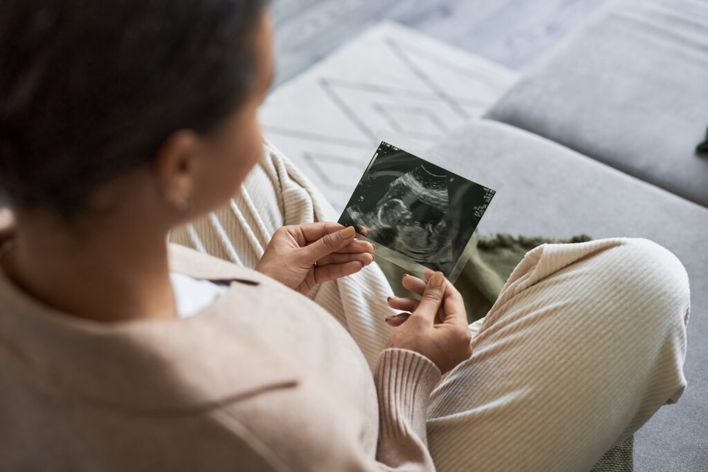 Young pregnant woman holding ultrasound print.