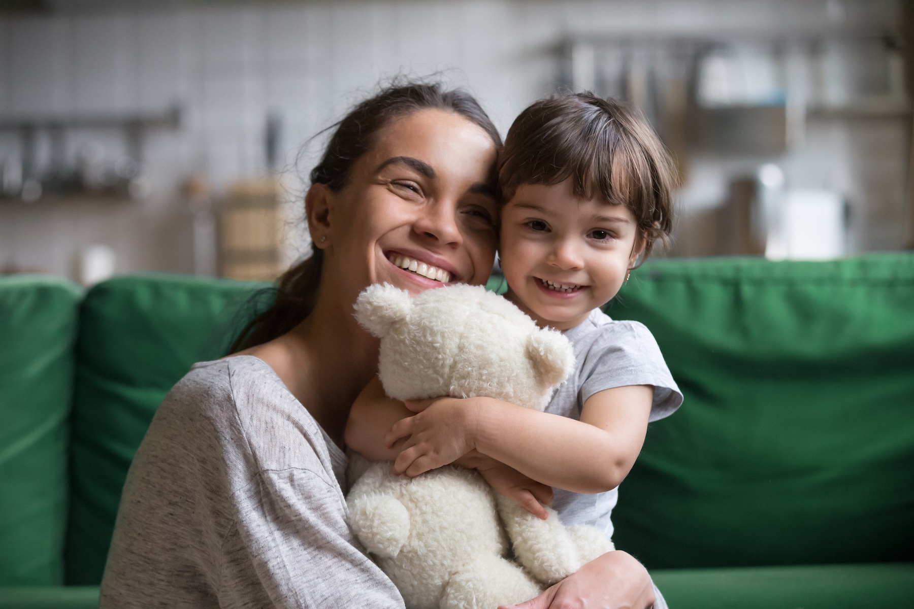 Smiling single young mom embracing preschool daughter with toy