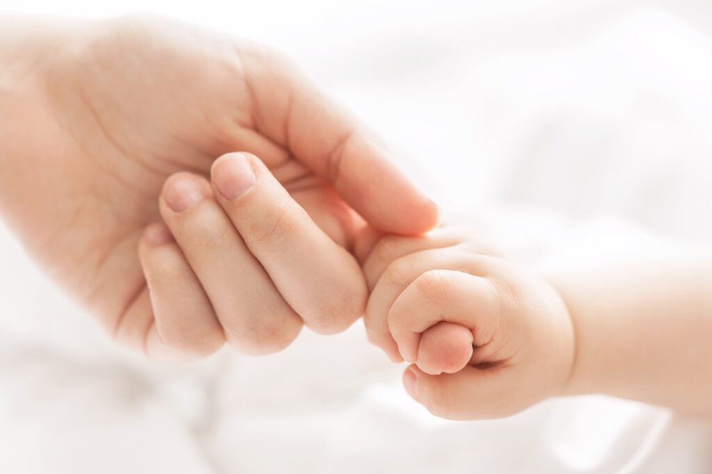 Close up of baby holding mother's index finger in its fist